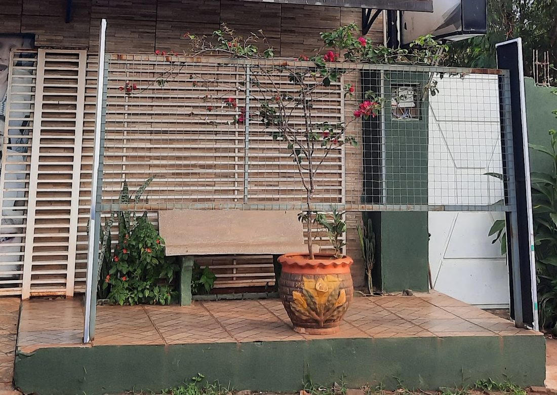 Entrada del consultorio Odontoliz, con banco, plantas y portón